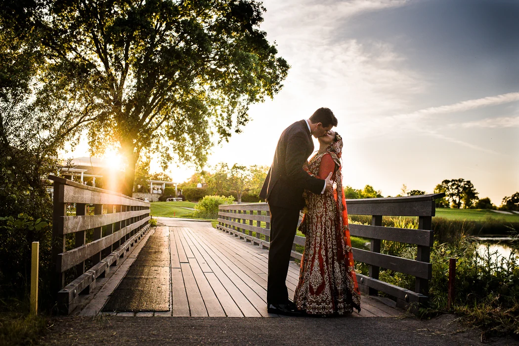 A couple embracing on a wooden bridge at sunset